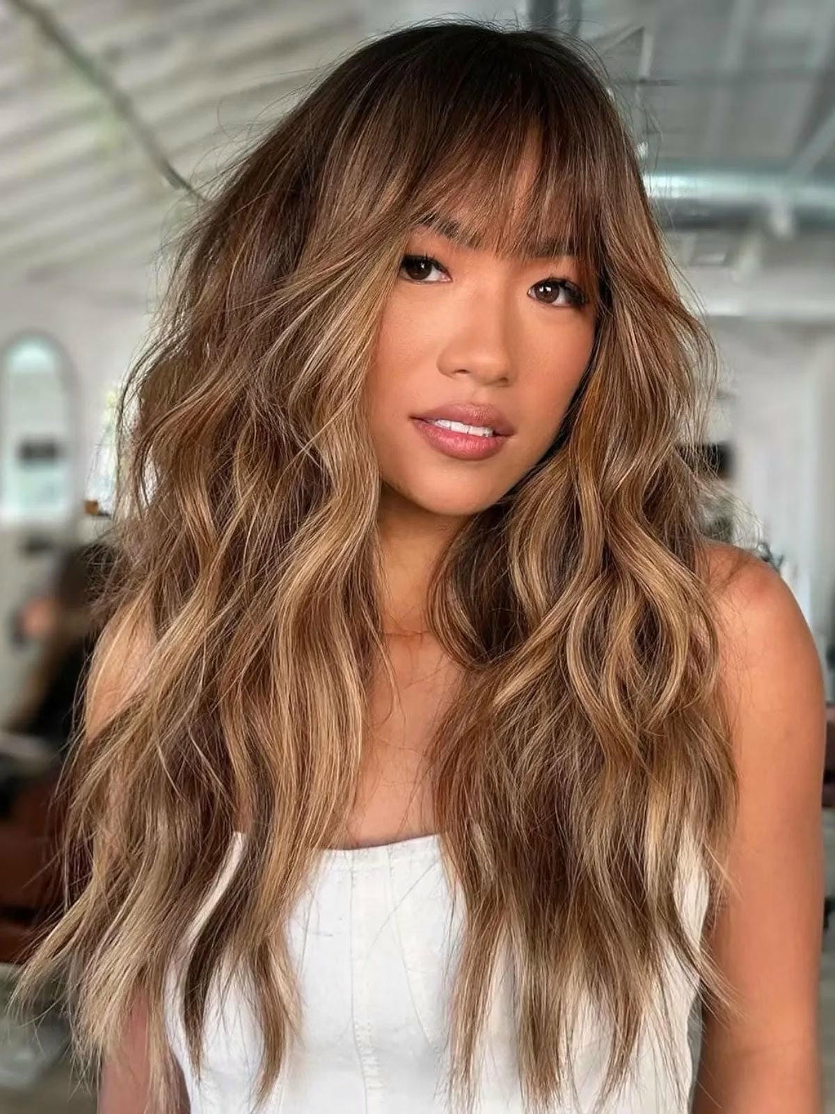 31. Wavy Chocolate Brown Hair with Soft Highlights and Bangs