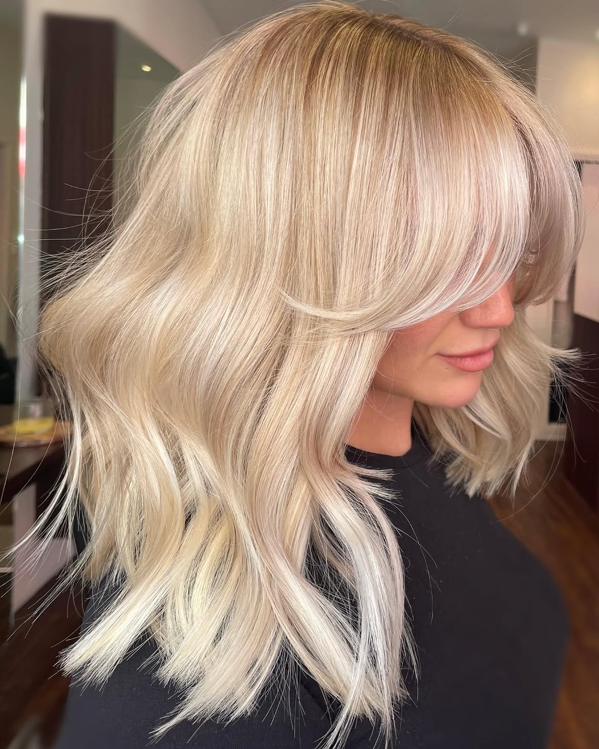 35. Textured Curtain Bangs with Bright Butter Blonde Waves