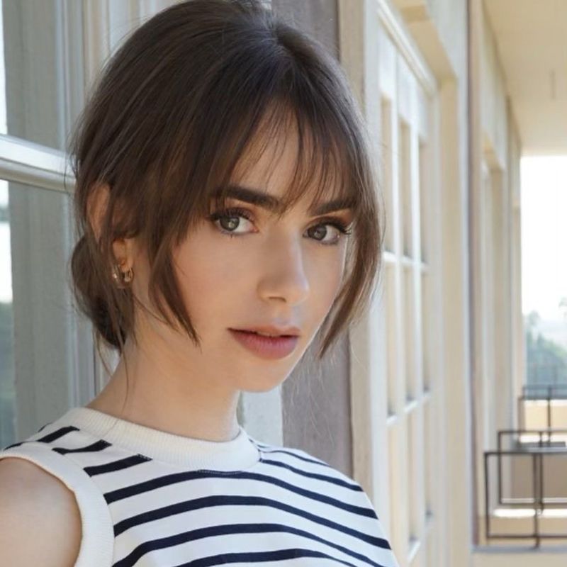29. Tousled Brunette Updo with Wispy Fringe