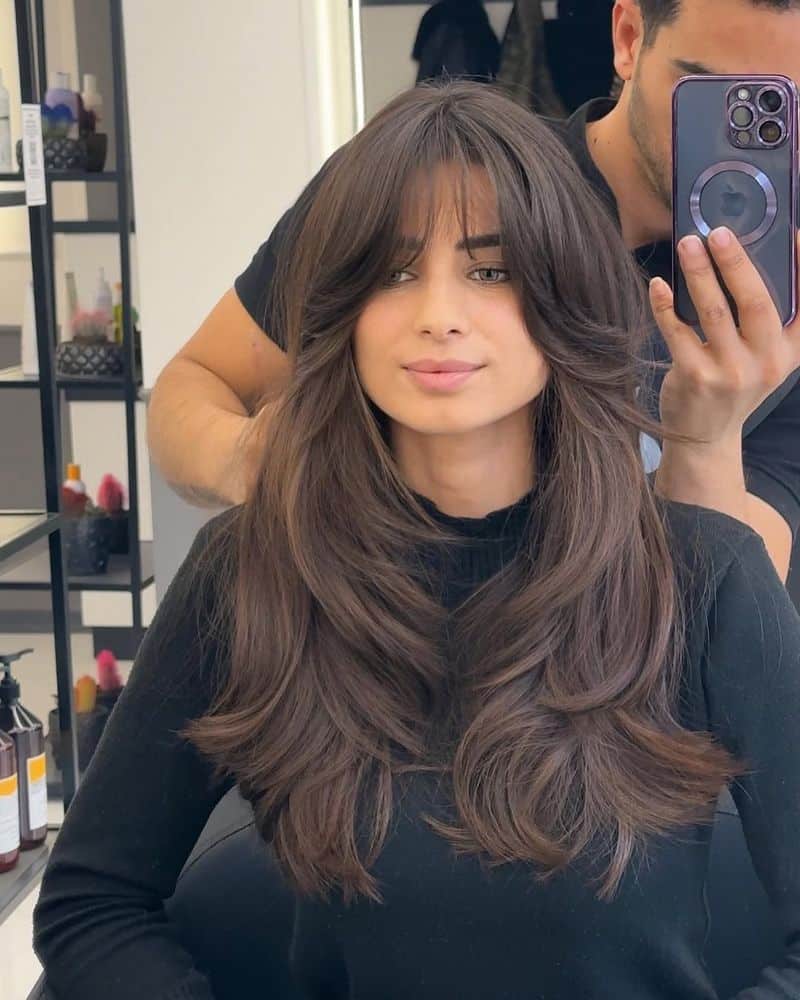 13. Voluminous Blowout Layers with Wispy Curtain Bangs