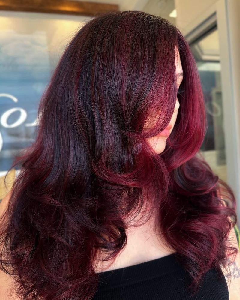 26. Black Cherry Layers with Face-Framing Curtain Bangs