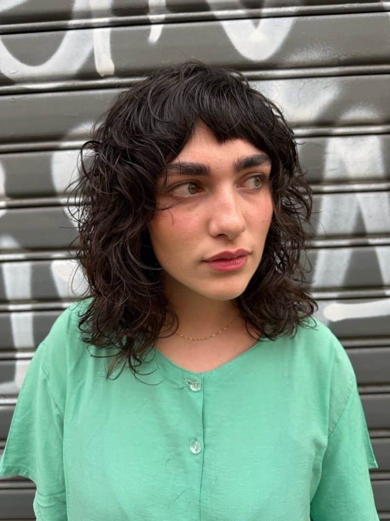 25. Curly Wolf Cut with Baby Bangs
