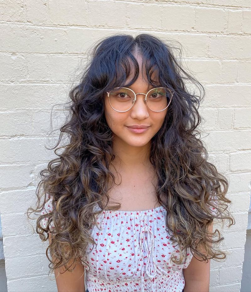 24. Dark Curly Shag with Highlights and Curtain Bangs