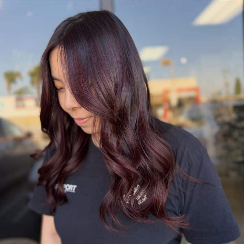 16. Glossy Maroon Waves with Side-Swept Bangs