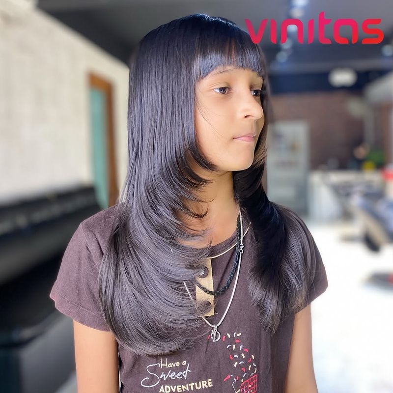 25. Sleek Feathered Layers with Straight Bangs