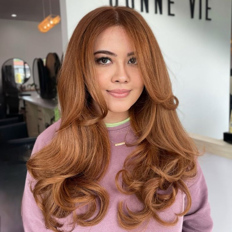 24. Warm Amber Blowout with Curtain Bangs